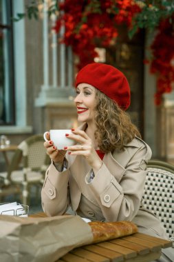 Bereli bir kadın açık havada kahve ve baget seviyor.