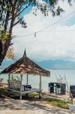 Arka planda Lombok 'a bakan sazdan çatılı bir kulübe, Gili Air.
