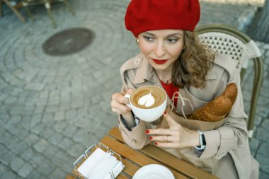 Bereli bir kadın açık havada kahve ve baget seviyor.
