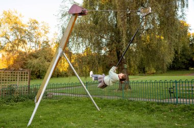 Kız çocuk parkındaki teleferik hattında gezmekten zevk alıyor.