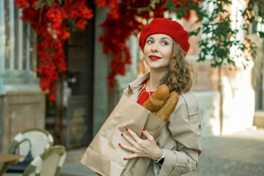 Bej yağmurluk ve baget giyen kırmızı bereli şık bir kadın.