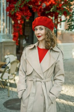 Kırmızı bereli ve trençkotlu çekici bir kadın. Şehir tarzı.