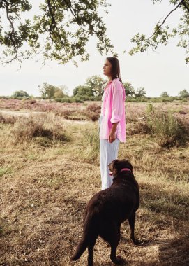 Kahverengi labrador köpeği tarlada olan bir kadın.