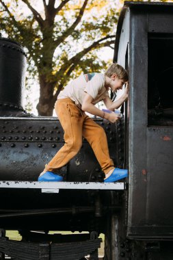 Genç çocuk parktaki eski trende oynuyor.