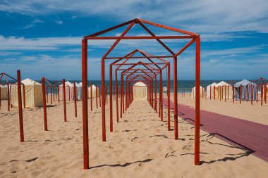 Deniz kenarındaki kırmızı kutuplar ve çizgili kulübelerin simetrisi