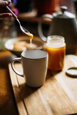 Kaşıktan fincana bal damlıyor.