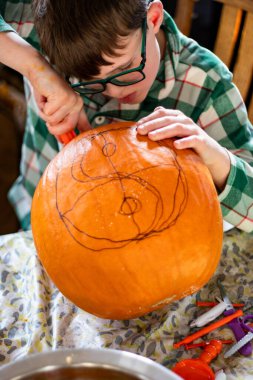 Çocuk oyma tasarımı mutfak masasındaki balkabağına çizilmiş.