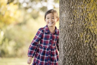 Mutlu kız sonbaharda bir ağacın arkasında saklanıyor.