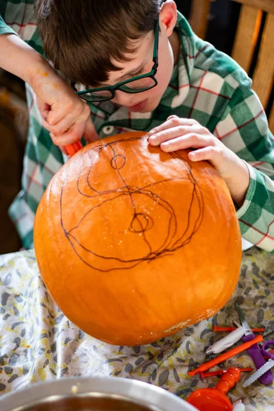 Çocuk oyma tasarımı mutfak masasındaki balkabağına çizilmiş.