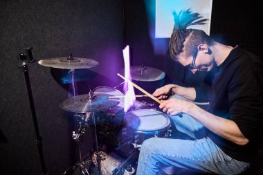 Stüdyoda renkli ışıkları olan genç bir davulcu