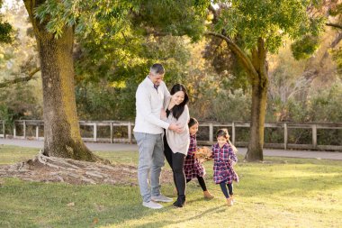 Parkta ailelerin etrafında koşuşturan kız kardeşler