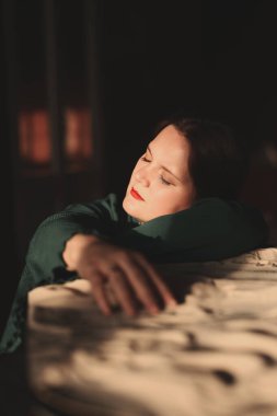 Kadın, sıcak ışıkta, taş yüzeyde huzur içinde dinleniyor.