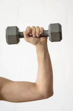 Kapalı alanda gri bir dambılı kaldırırken yakın plan.