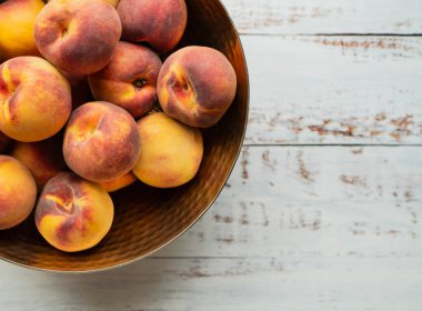 Üst manzara, beyaz ahşap arka planda şeftali kasesini kapat..