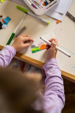 Küçük kız içeride bir zanaat aktivitesi yapıyor, sanat projesi yaratıyor.