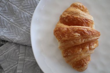 Beyaz tabakta tek bir kruvasan.