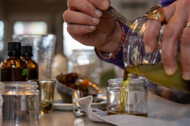 Kadın bitkisel merhemi küçük konteynıra boşaltıyor.