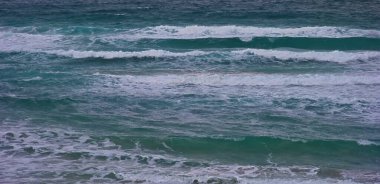 Turkuaz suda beyaz köpükle dalgalanan okyanus dalgaları.