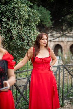 Roma, İtalya 'da Colosseum yakınlarında kırmızı elbiseli bir kadın duruyor.