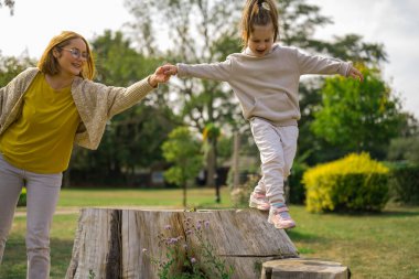 Anne ve kızı, parkta birlikte vakit geçiriyorlar.