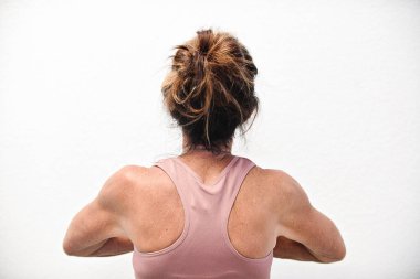 Leylak rengi aktif giysili omuzları olan bir kadının arka görünüşü.