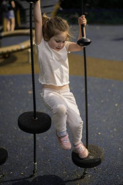 Küçük kız tırmanıyor, oynuyor ve oyun alanında eğleniyor.