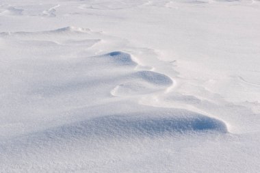 Rüzgârlı kar, kıvrımlı ışık ve gölge dokularını sergiliyor