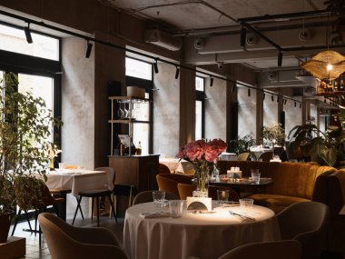 Konforlu koltukları ve doğal ışığı olan şık bir restoran.