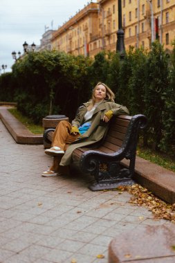 Parktaki bankta spor ayakkabılarıyla rahatlayan bir kadın.