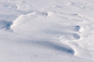 Rüzgârlı kar, kıvrımlı ışık ve gölge dokularını sergiliyor
