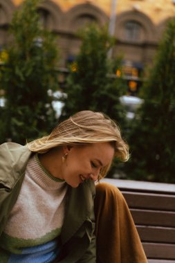 Parktaki bankta oturmuş gülümseyen mutlu kadın.