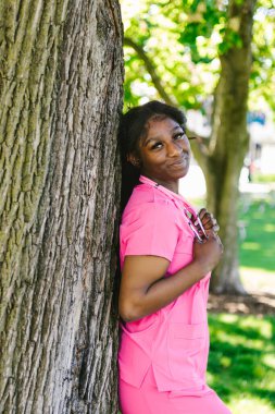 Dışarıda steteskoplu önlüklü mutlu siyah hemşire.