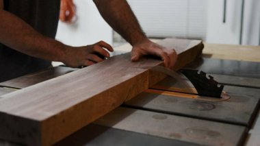 Eller, kalın bir tahta parçasını masa testeresine yönlendirir.