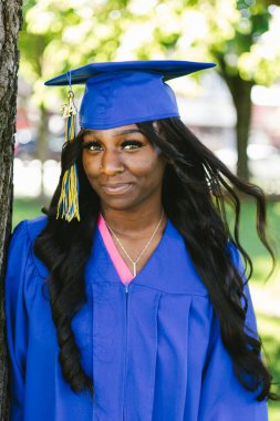 Mezun olmuş kep ve cüppeli genç siyahi kadın dışarıda.