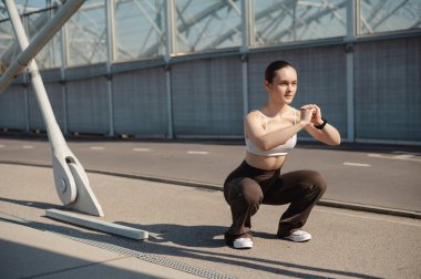 Güneşli bir günde dışarıda çömelmiş bir kadın gösteri yapıyor
