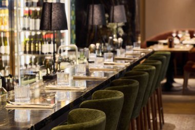 Modern bir restoranda, yumuşak ışıklandırmalı şık bir bar oturma yeri.