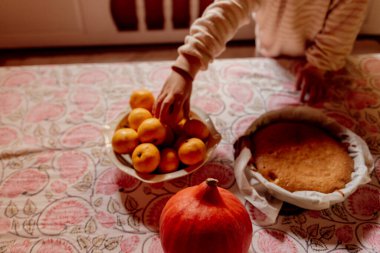 Çocuk portakalları desenli masa örtüsünde tutuyor