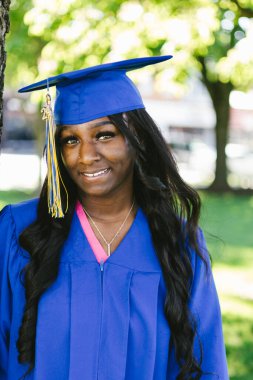 Şapkalı ve cüppeli, gülümseyen siyah kadın.