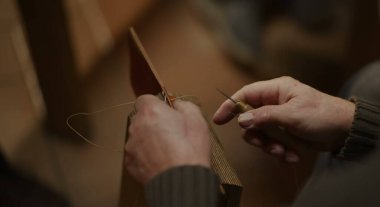 Odaklanmış bir çalışma alanında, ellerinle deriyi ağda ve iplikle dikersin.