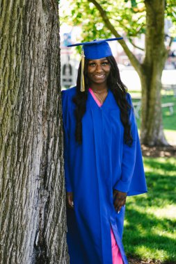 Siyahi kadın kep ve cübbeyle mezun olurken neşeyle gülümsüyor.