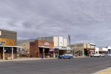 Bulutlu gökyüzünün altında batı binalarıyla dolu bir cadde.