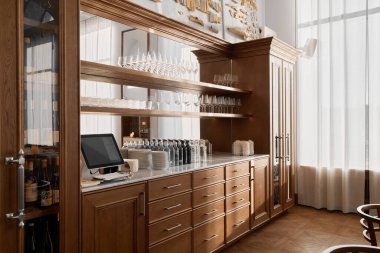 Cam eşyalar ve içkilerle donatılmış zarif bir ahşap bar.