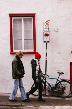 Bisikletli iki kadın şehir merkezinde yol boyunca birlikte yürüyorlar.
