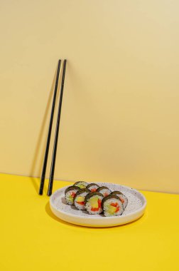 Suşi parlak bir arka planda bir tabakta yuvarlanıyor.