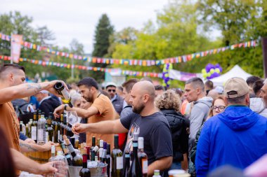 Bir adam şarap festivalinde bardağa şarap doldurur.