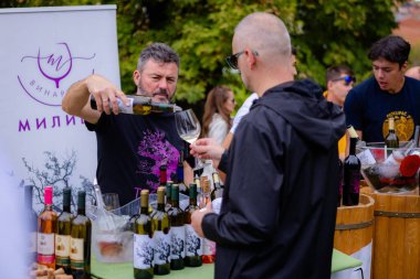 Bir satıcı şarap festivalinde bir müşterinin bardağına şarap döker.