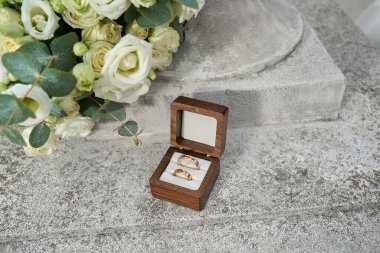 Bir buket beyaz gülle ahşap bir kutuda evlilik yüzükleri..