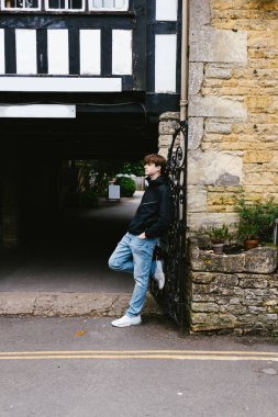 Genç çocuk Cotswold köyündeki taş işçiliği binasında poz verdi.