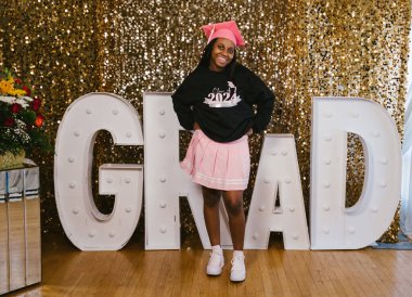 Siyahi genç kız mutlu ve başarıyla gülümsüyor.