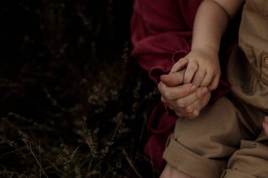 Bebek ve anne uzun çalılıklarda el ele tutuşuyorlar.